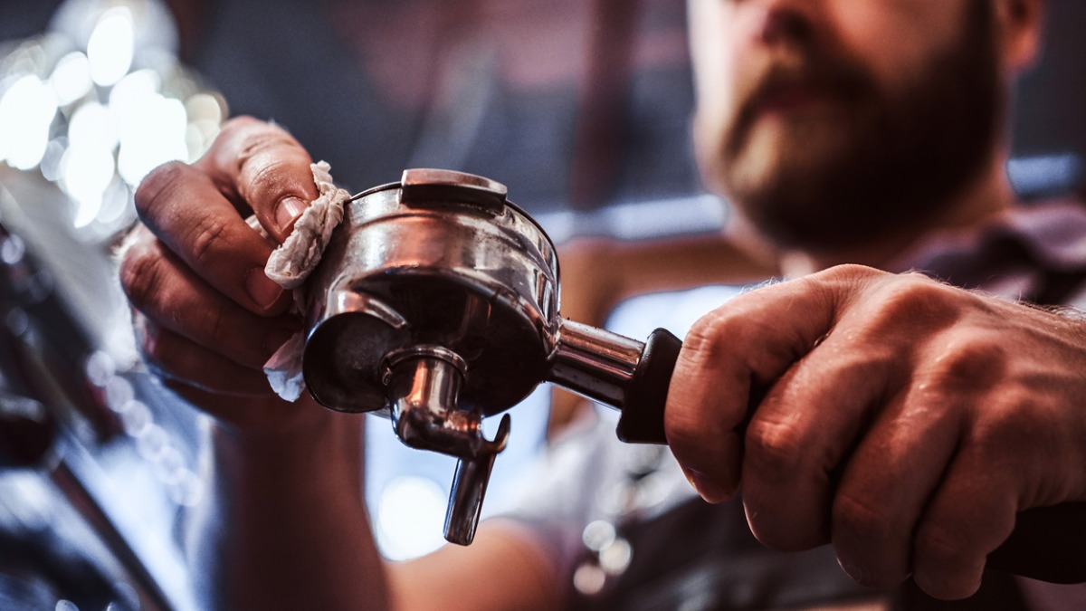 homme qui prépare nettoie machine à espresso